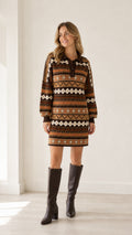 Front full-length view of model wearing brown geometric pattern polo neck sweater dress with tall black boots