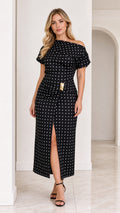 Front view of model wearing black polka dot asymmetrical midi dress with front slit