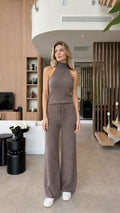Front view of woman wearing taupe brown sleeveless mock neck knit top and wide leg lounge pants