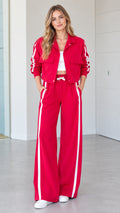 Front full view of woman wearing red 2-piece side stripe cropped jacket and wide-leg track pants set