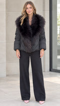 Front view of model wearing black quilted puffer jacket with plush black faux fur collar and wide-leg trousers
