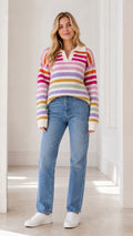 Front full view of woman wearing cream multicolor striped polo sweater with blue jeans