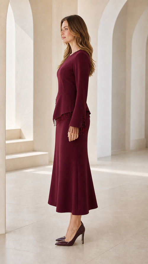 Side view of model wearing burgundy long sleeve peplum midi dress