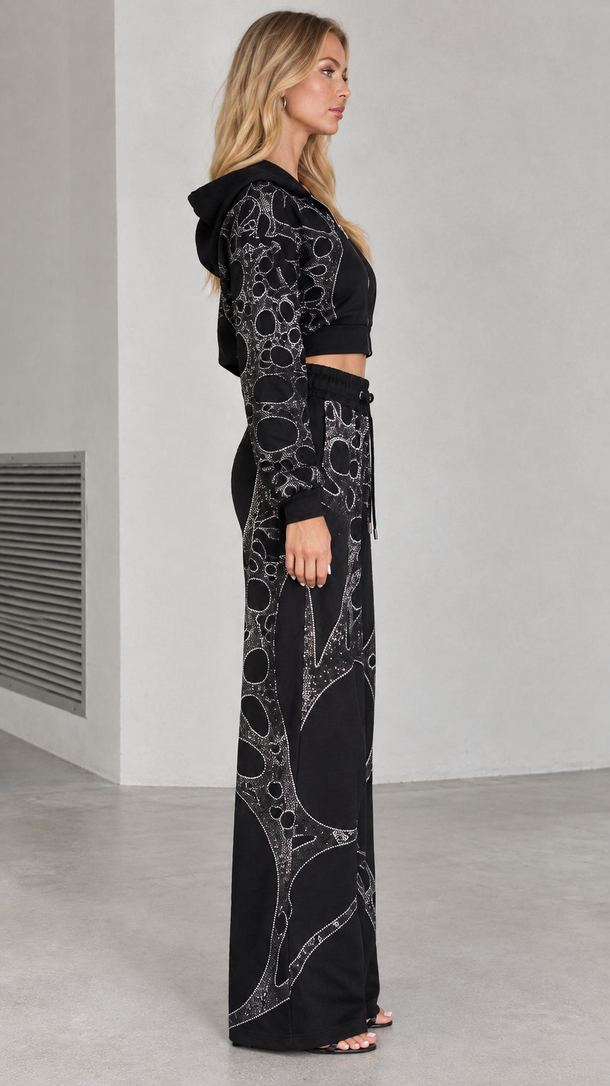 Side profile view of woman wearing black rhinestone tracksuit set