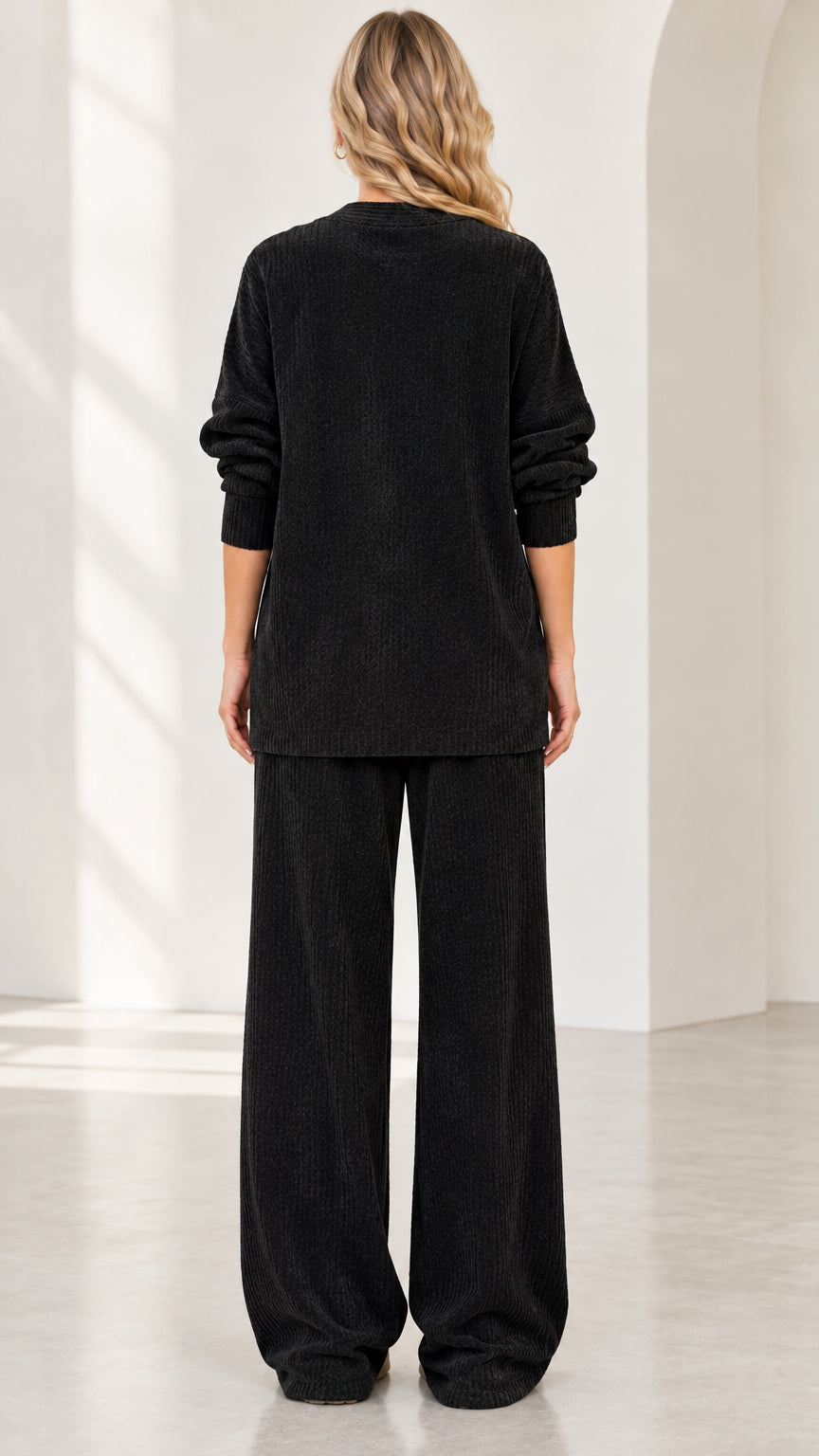 Back full view of woman wearing black relaxed fit lounge set with wide leg trousers