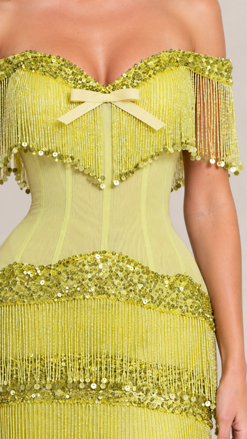 Close-up detail of sweetheart neckline, bow accent, boning, and sequin fringe trim